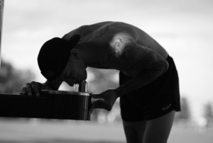 A photo of a man drinking from a water fountain