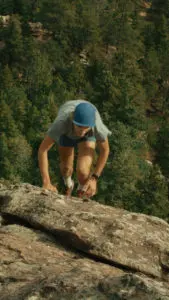 A photo of a man clambering up some rocks