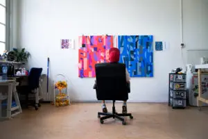 A photo of someone sitting in a chair looking at some art on the wall