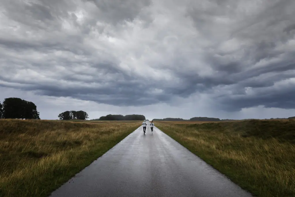 A photograph of two people running down an open road