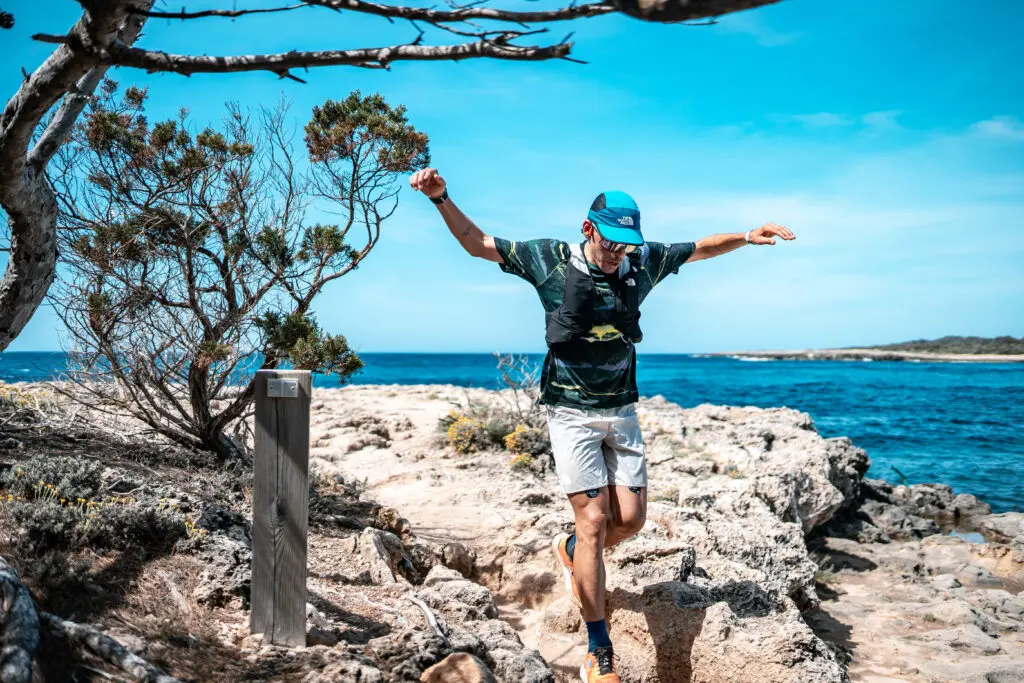A photo of a man running with a rocky seaside backdrop