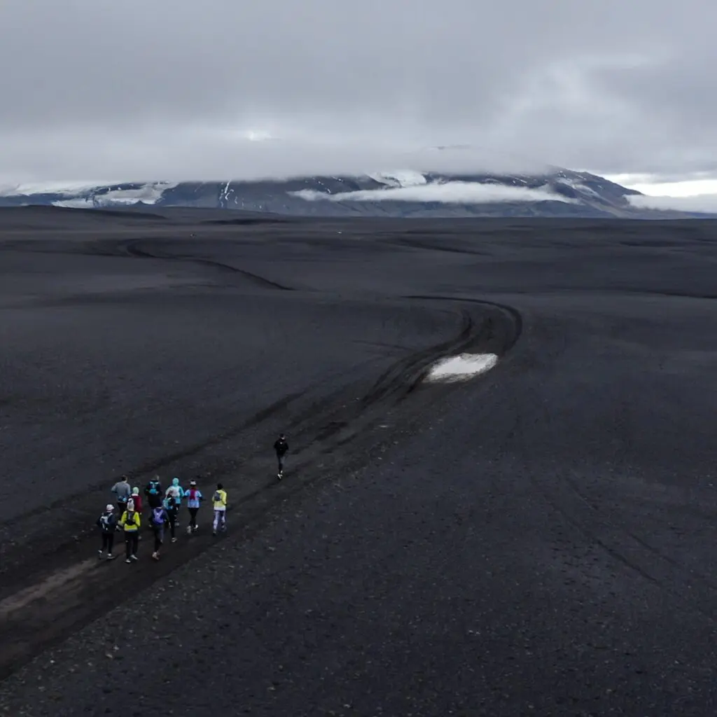 A photograph of some people walking through a dirt track