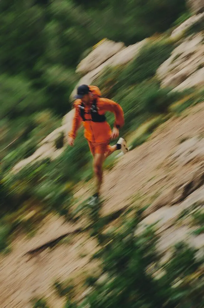 A photo of a man running downhill on trails