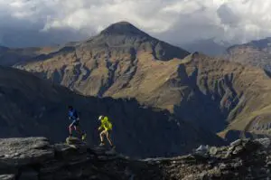 A photograph of two people running in the mountains